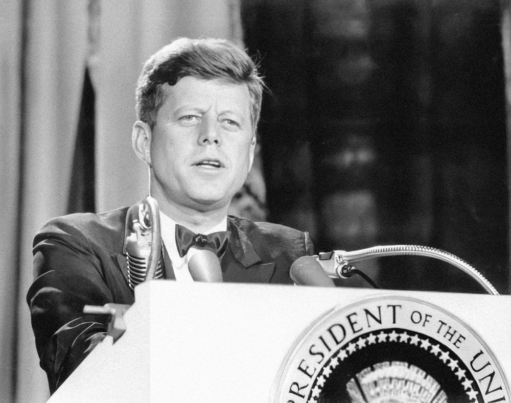 a man in a suit and tie standing at a podium