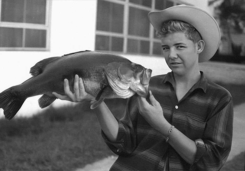 a man in a cowboy hat is holding a fish