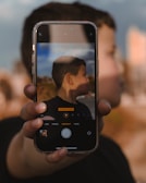 Side profile photo being taken with a smartphone against a softly lit background