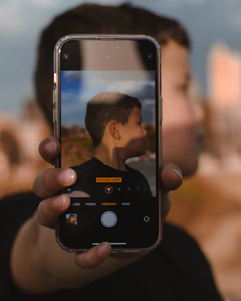 Close-up of a hand holding a smartphone capturing a clear iris photo with side lighting.