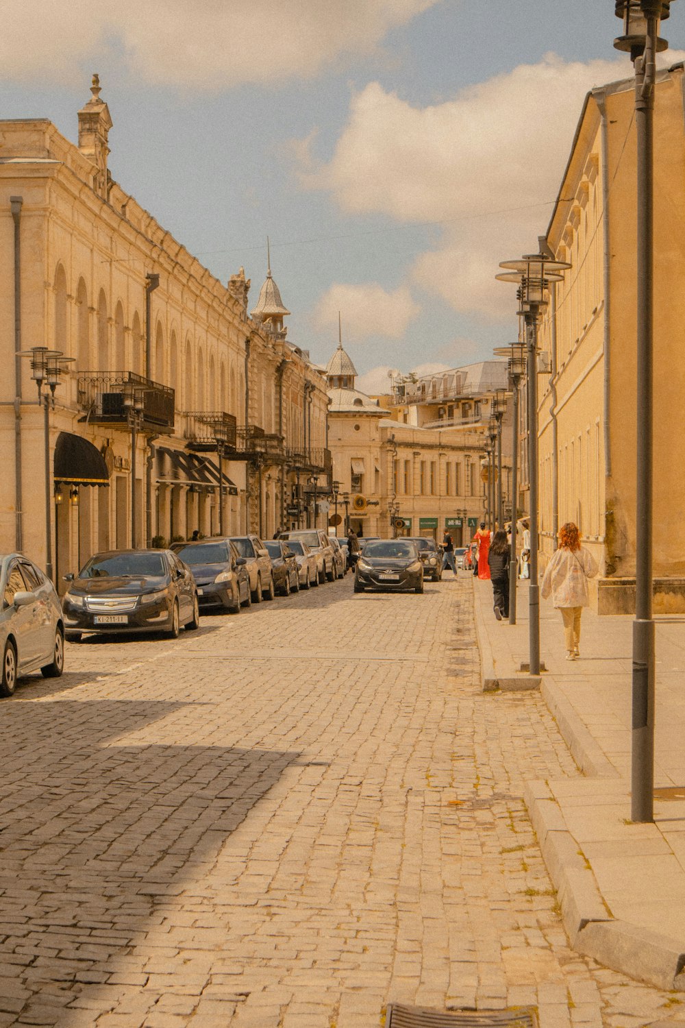 uma rua de paralelepípedos ladeada de carros estacionados