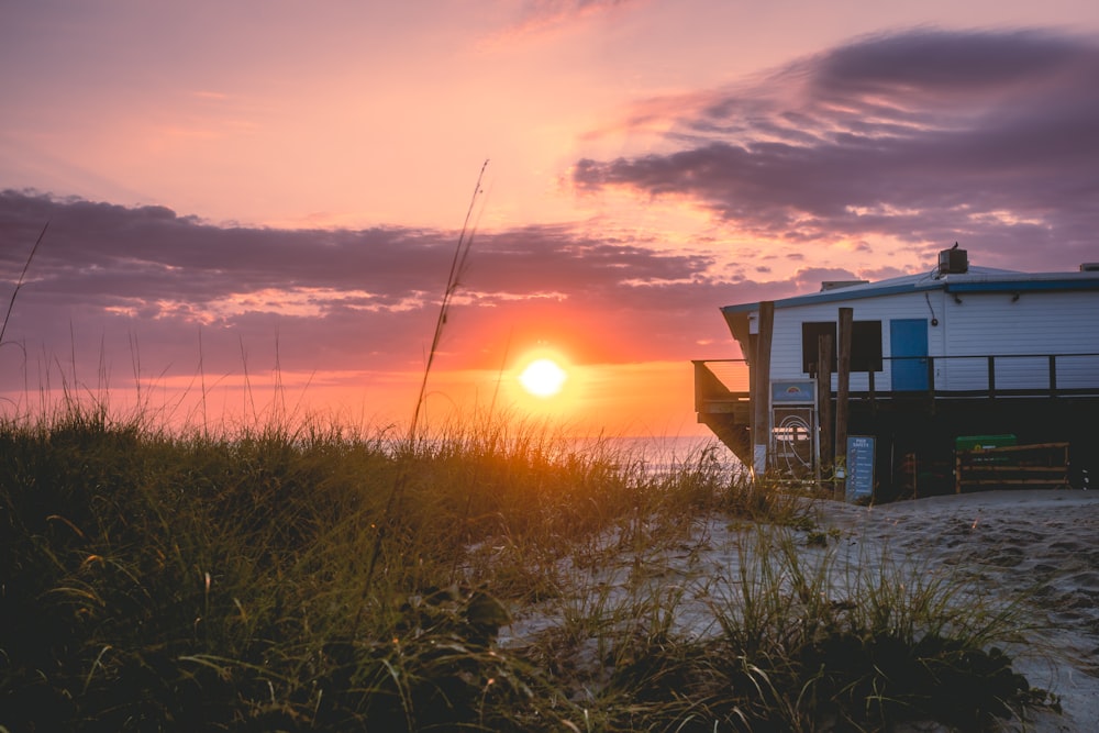 the sun is setting behind a beach house