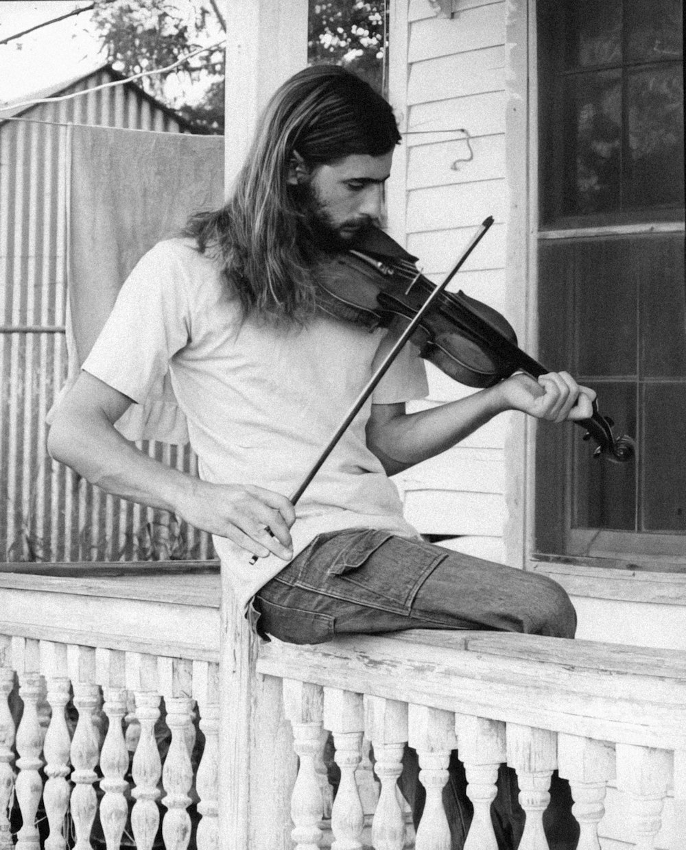 a man sitting on a porch playing a violin