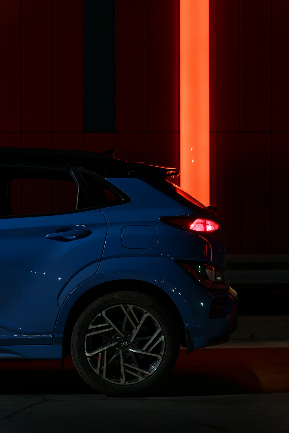 Un coche azul aparcado frente a una pared roja