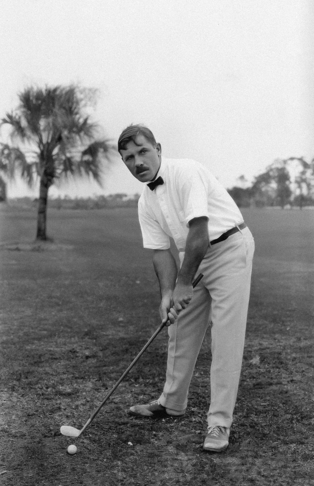 a black and white photo of a man playing golf
