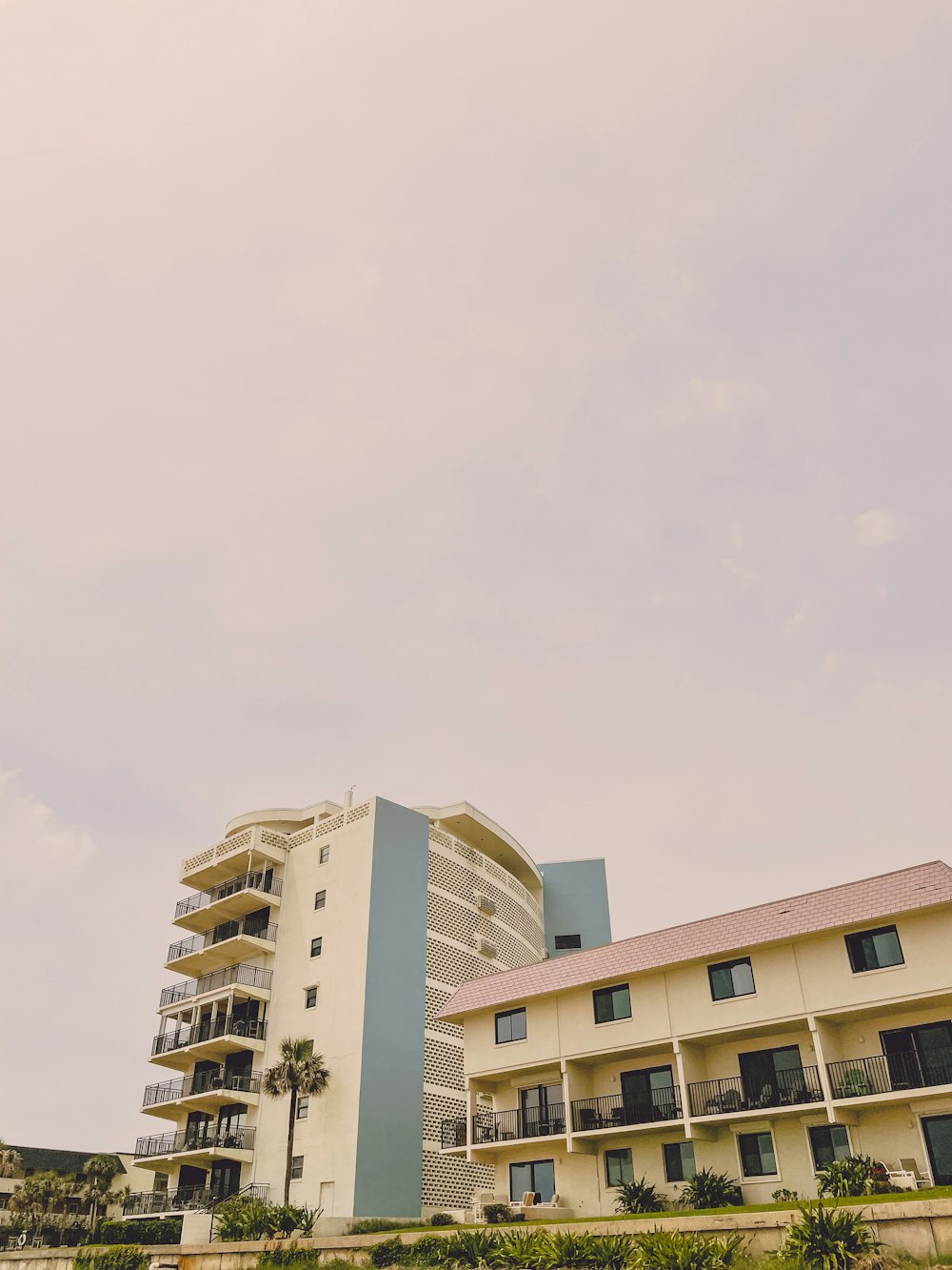 a tall white building sitting next to a lush green field