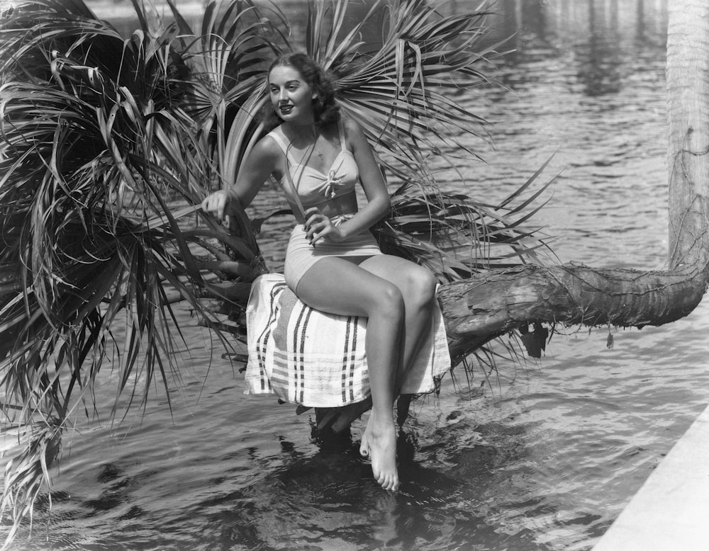 a woman sitting on a log in the water