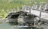A traditional wooden bridge crossing a rushing mountain stream.