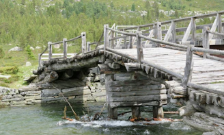 A rustic wooden bridge crossing a clear mountain stream