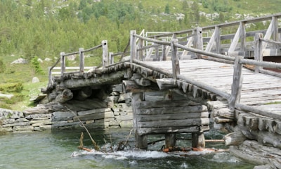 A traditional wooden bridge crossing a rushing mountain stream.