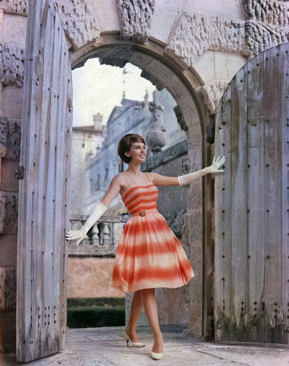 a woman in an orange and white dress is standing in a doorway