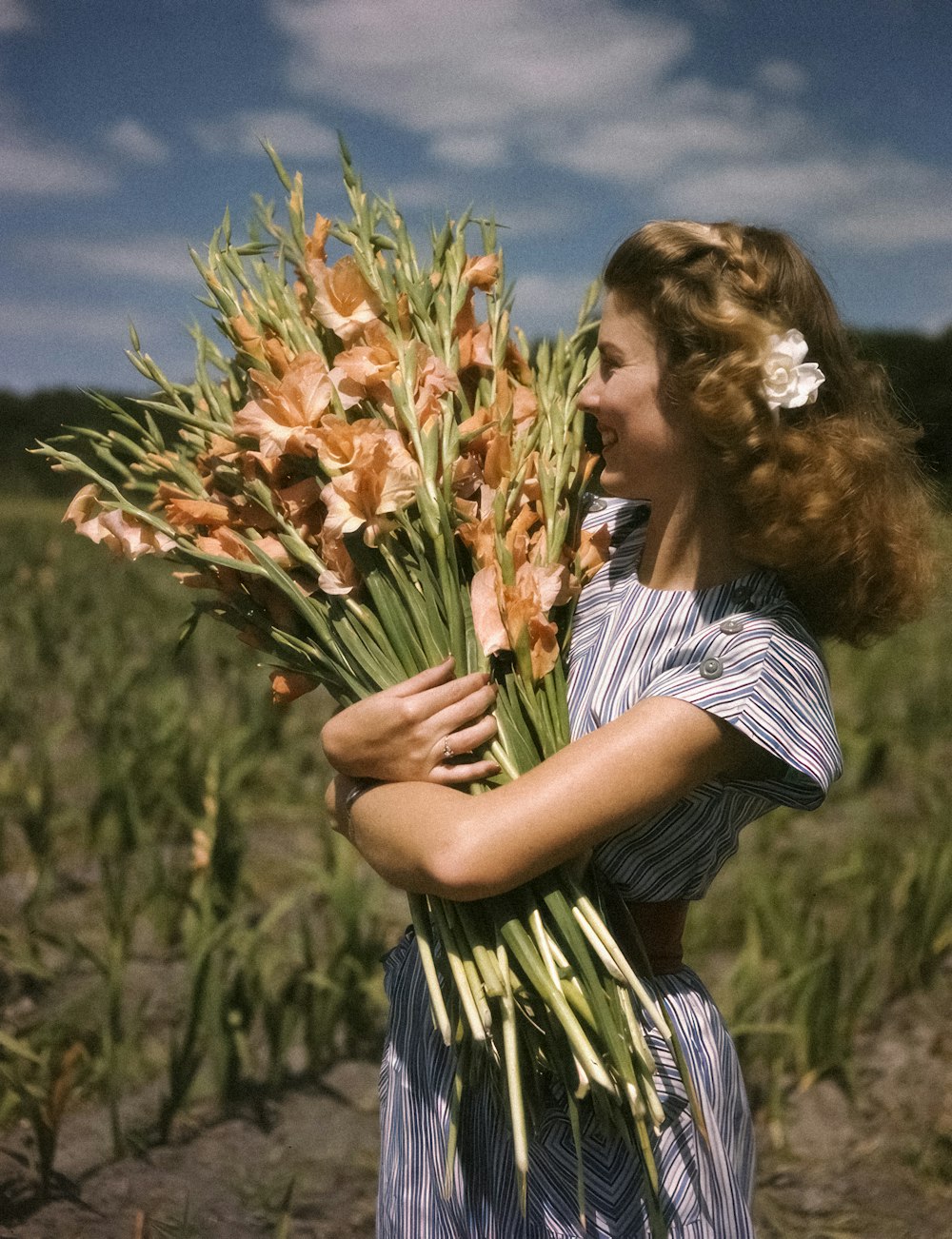 a woman holding a bunch of flowers in a field