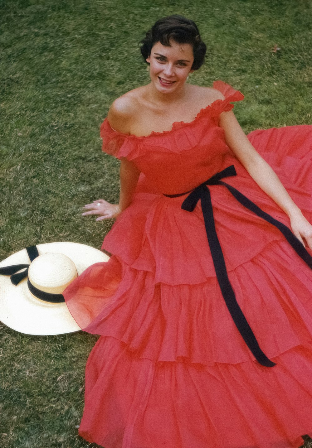 a woman in a red dress is sitting on the grass