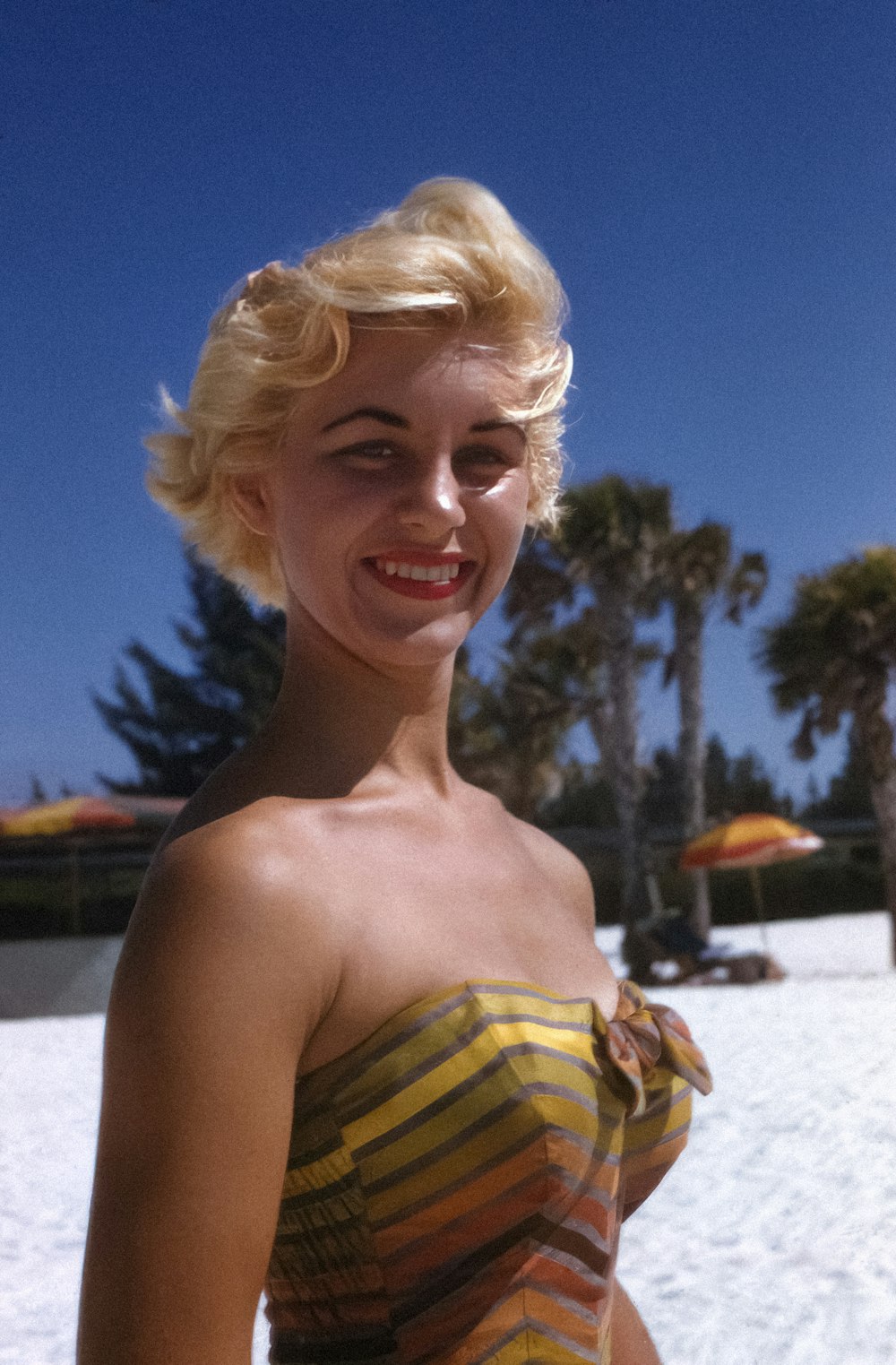 a woman standing on a beach with a smile on her face