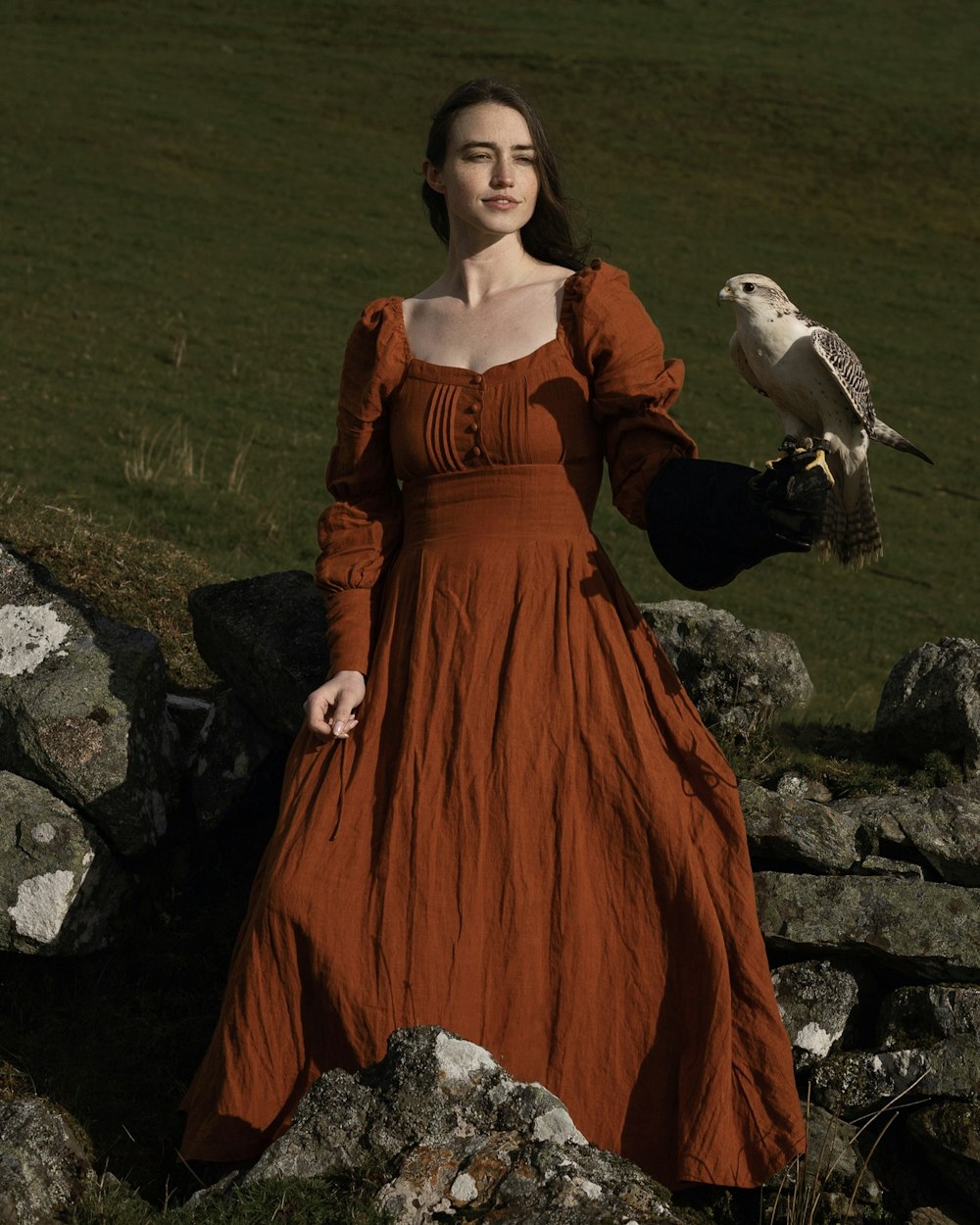 Eine Frau in einem orangefarbenen Kleid, die einen Vogel hält