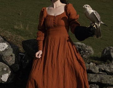 a woman in an orange dress holding a bird