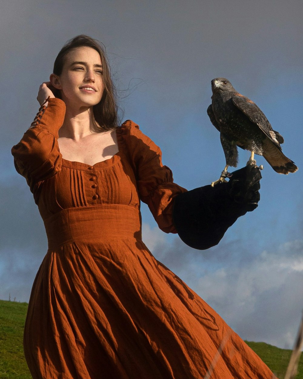 Eine Frau in einem orangefarbenen Kleid, die einen Vogel auf dem Arm hält