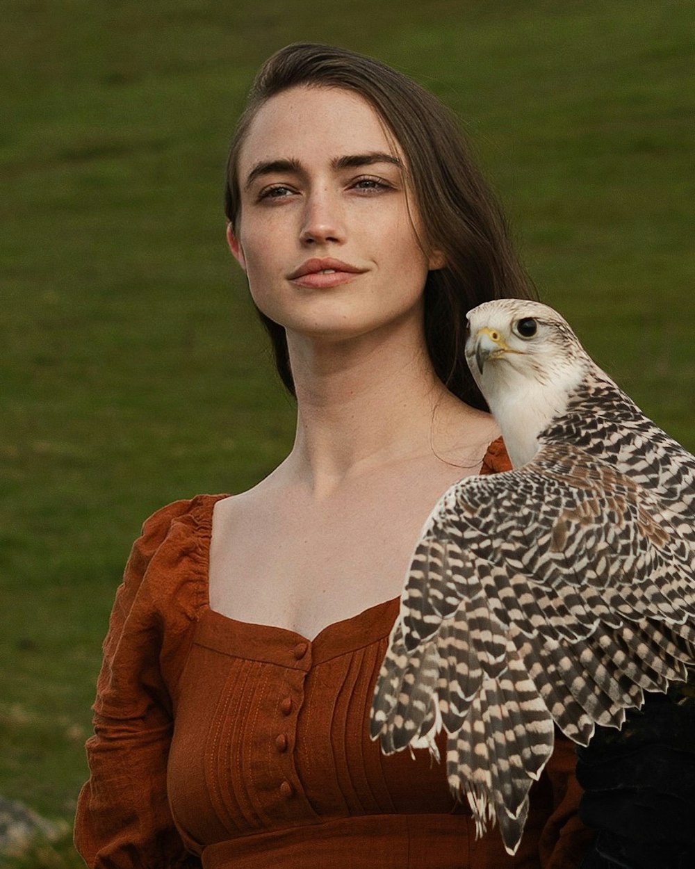 a woman holding a bird of prey in her hand