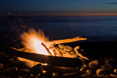 A cozy campfire setup under starry skies near the calm Mediterranean coastline.