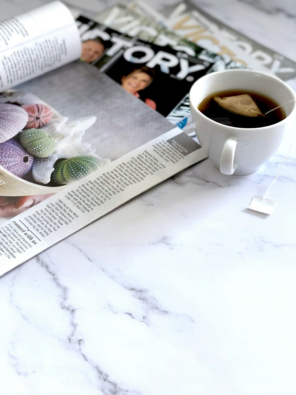 a cup of coffee sitting on top of a table next to a magazine