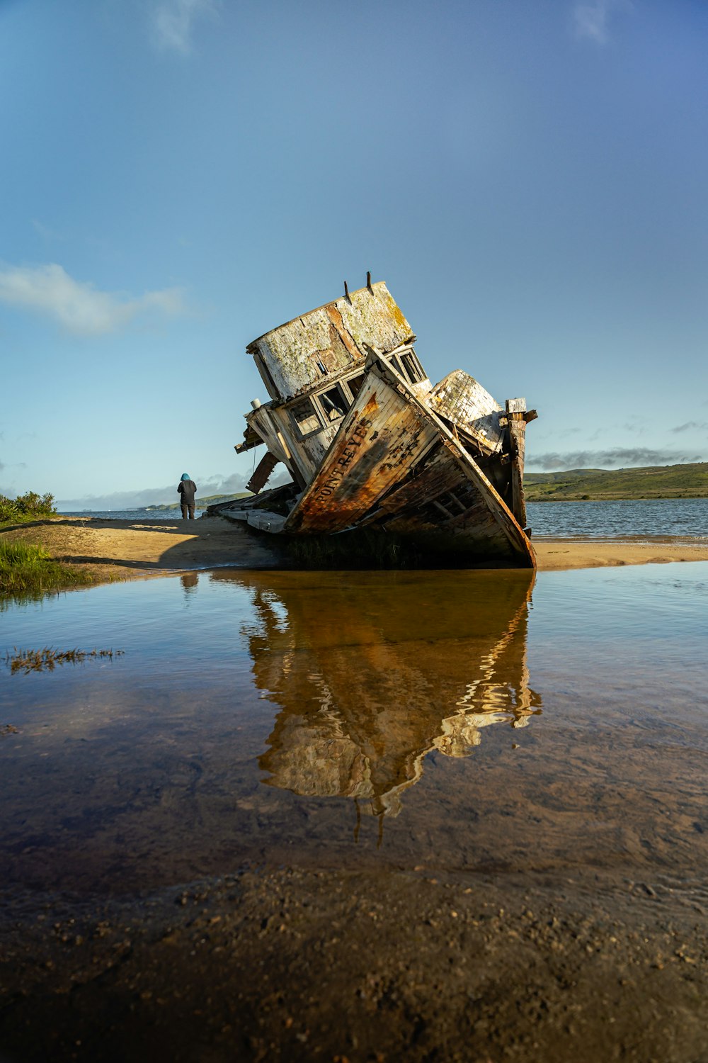 a boat sitting on top of a sandy beach next to a body of water