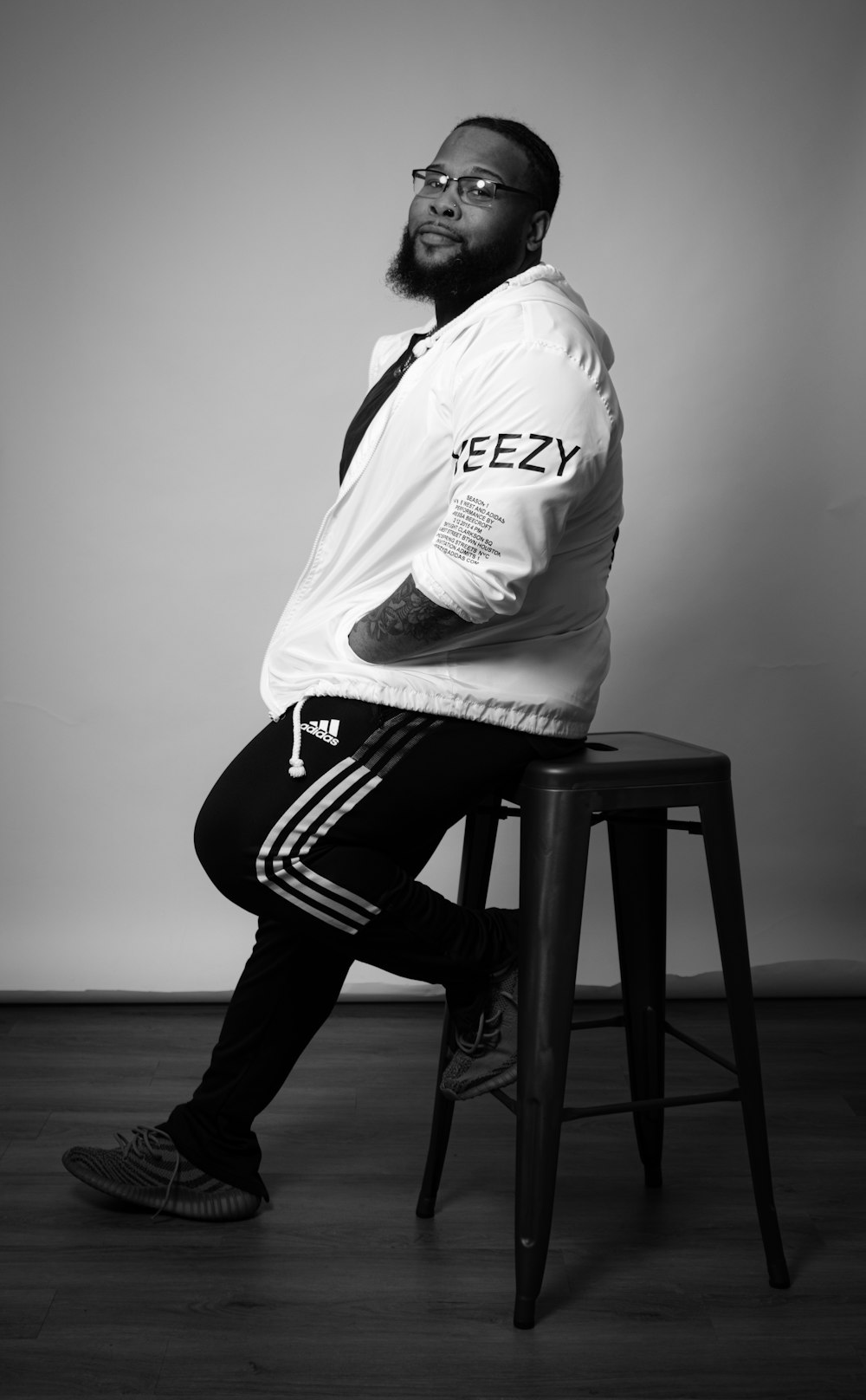 a black and white photo of a man sitting on a stool