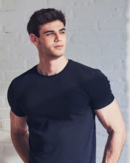 a man standing in front of a white brick wall