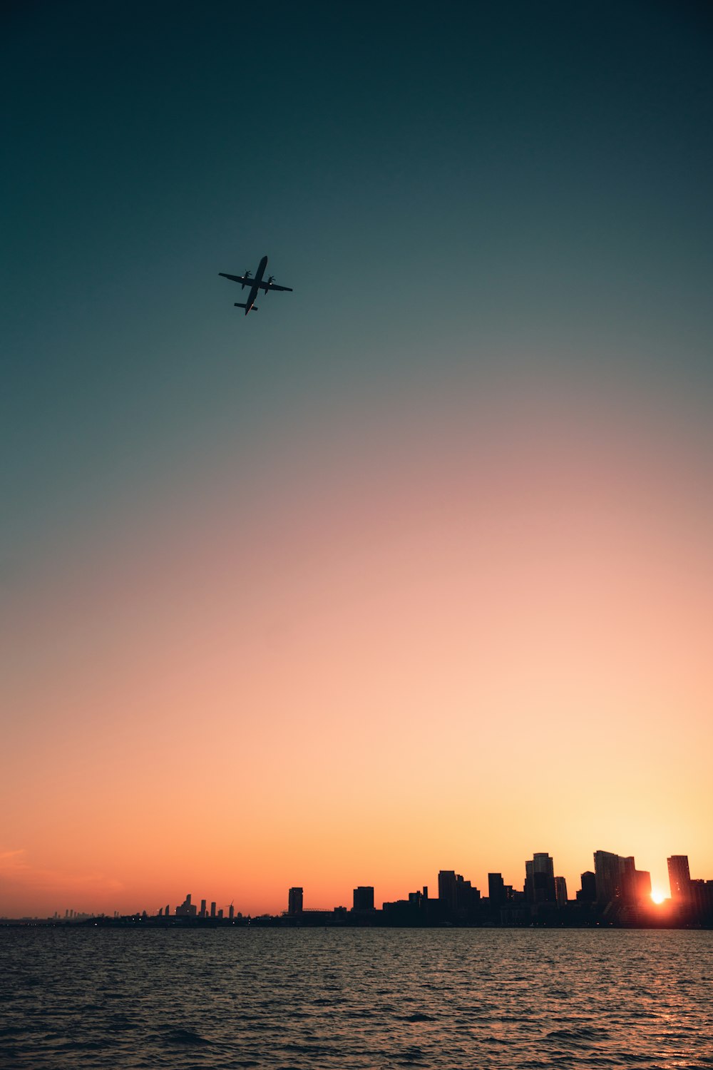 a plane flying over a city at sunset