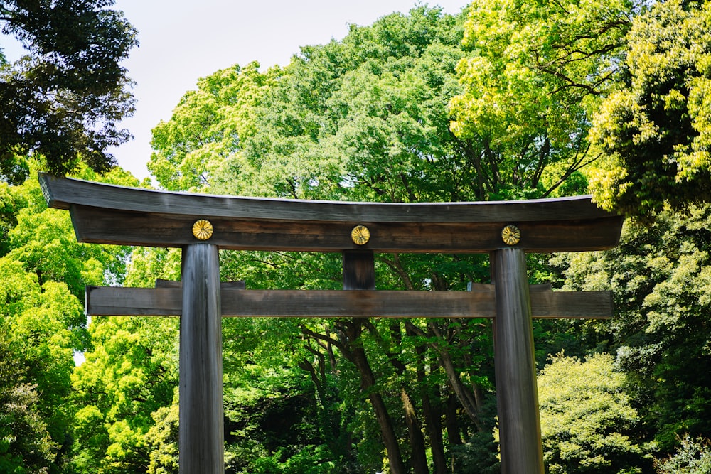 a large wooden gate in the middle of a forest