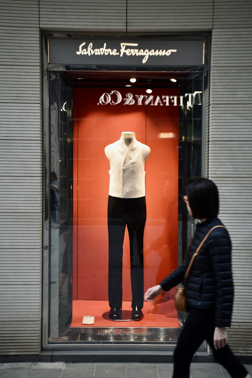 uma mulher passando por uma exibição de uma camisa branca e calças pretas