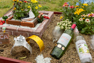 a bottle of wine sitting in a garden filled with flowers