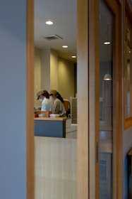 Smiling cleaning staff working efficiently in a bright, modern café kitchen.