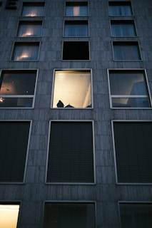 a tall building with several windows and a person standing in the window