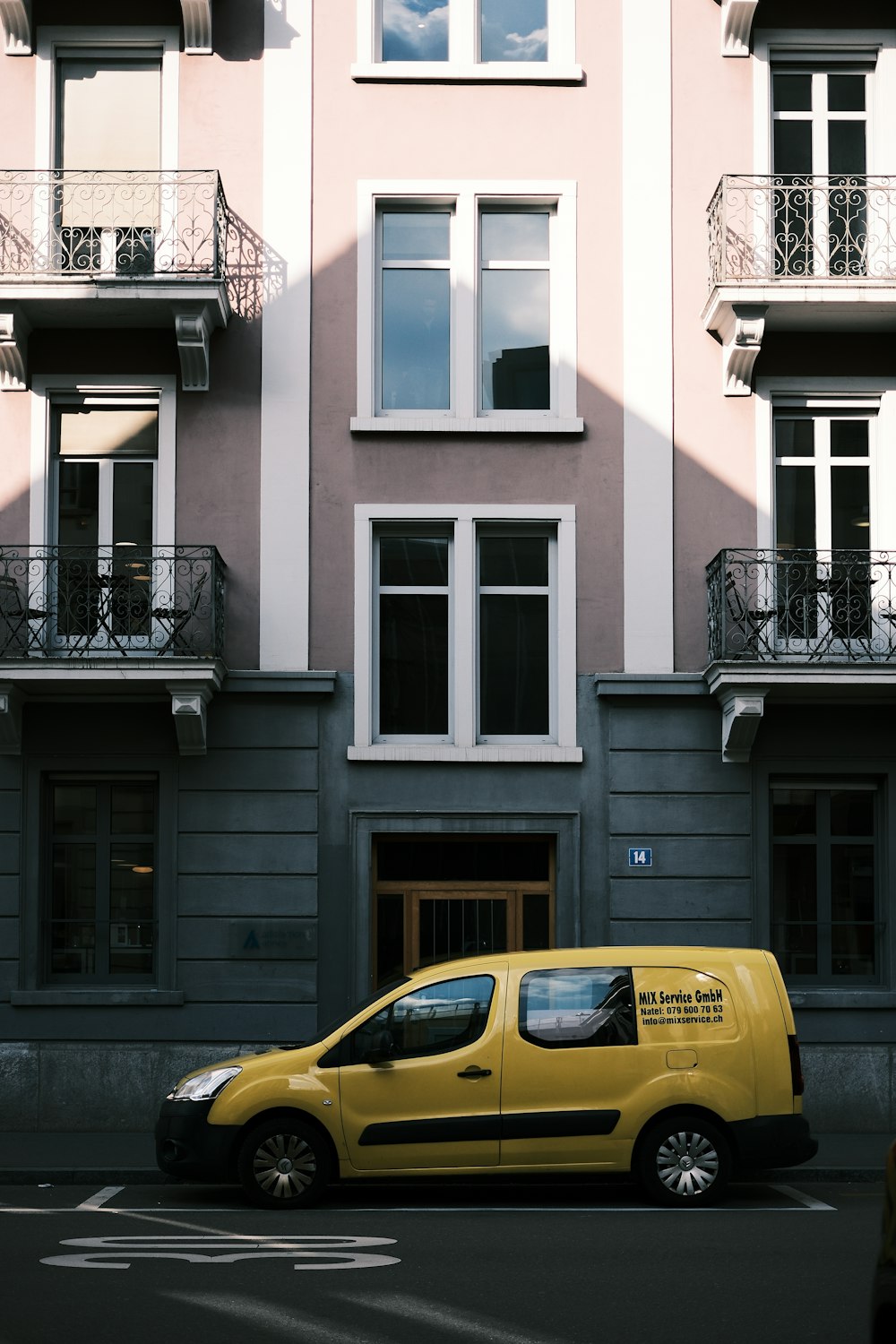 a yellow van parked in front of a tall building