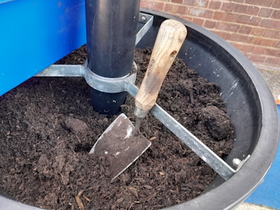 Close-up of a wooden-handled trowel and pruning shears resting on rich soil.