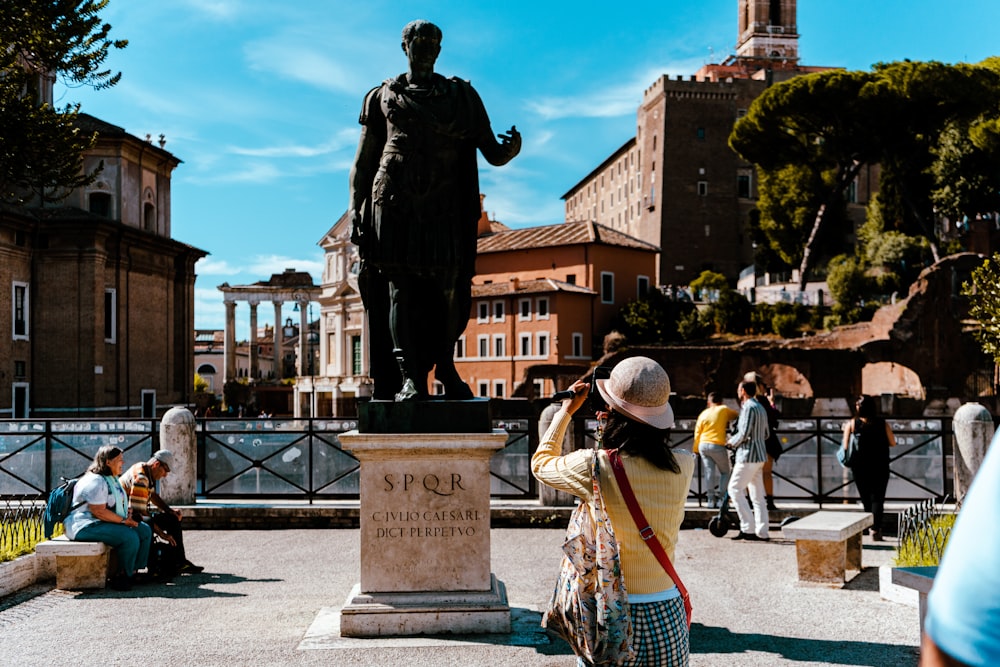 a woman taking a picture of a statue of a man