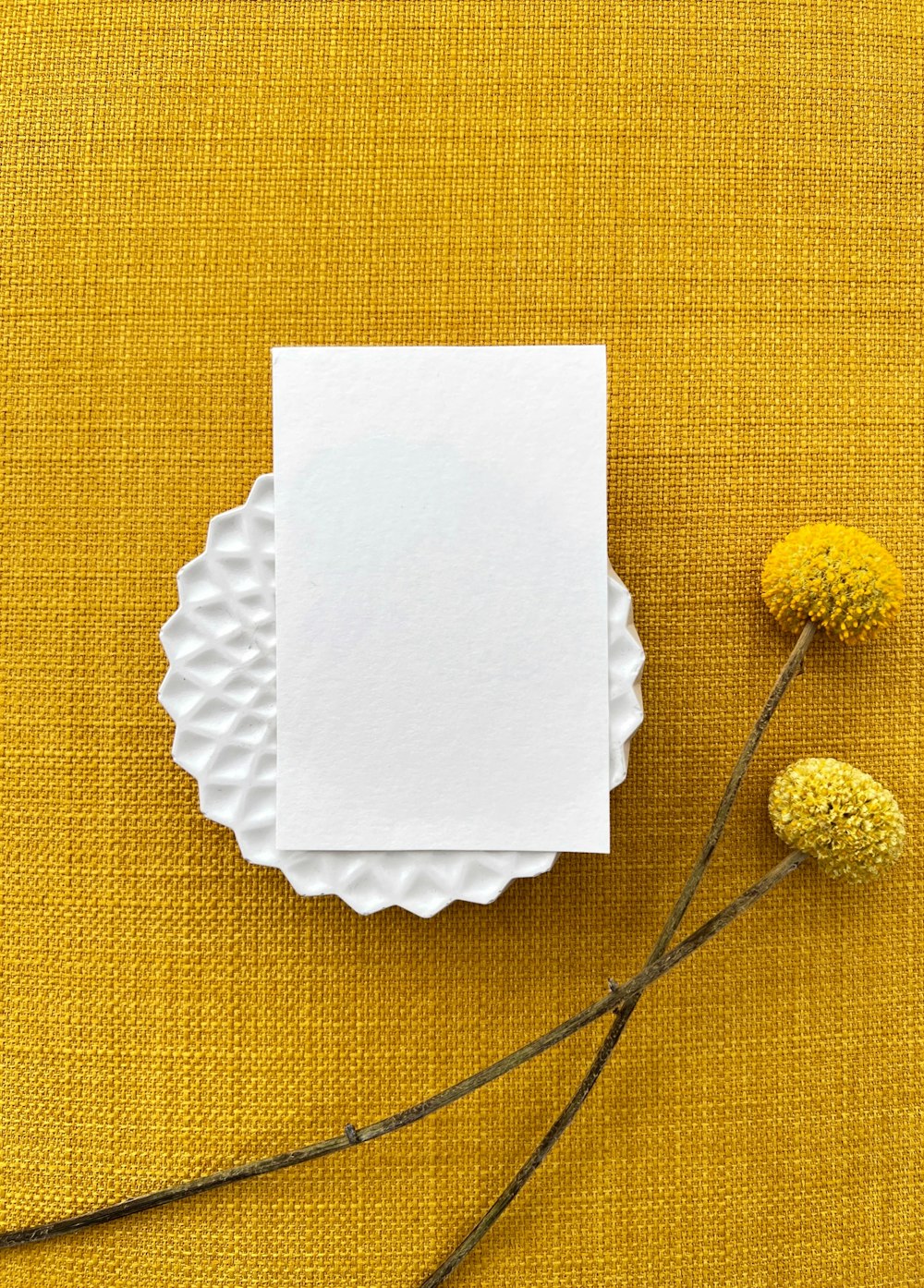 a yellow cloth with a white paper and some yellow flowers