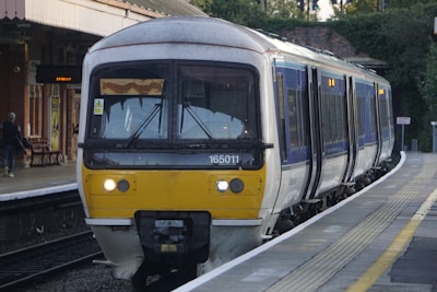 a yellow and white train pulling into hampton court station