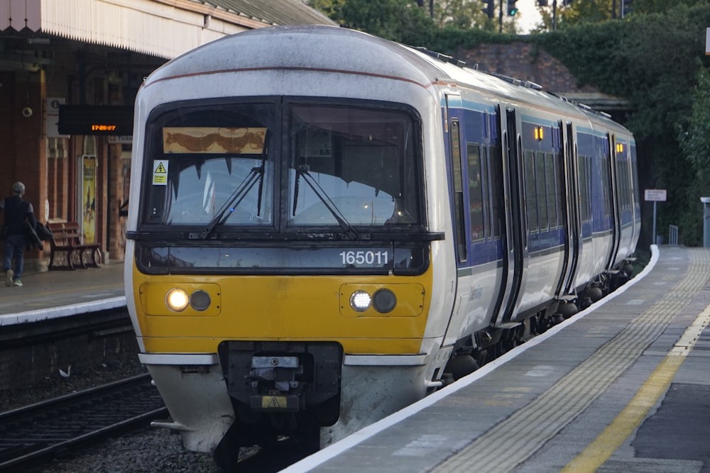 un train jaune et blanc entrant dans une gare