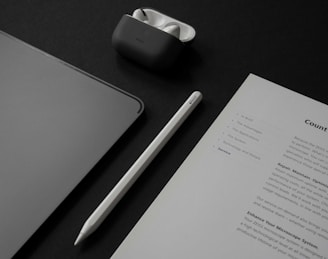 a table with a notepad, a pen, a cell phone, and a