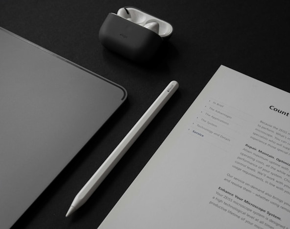 a table with a notepad, a pen, a cell phone, and a