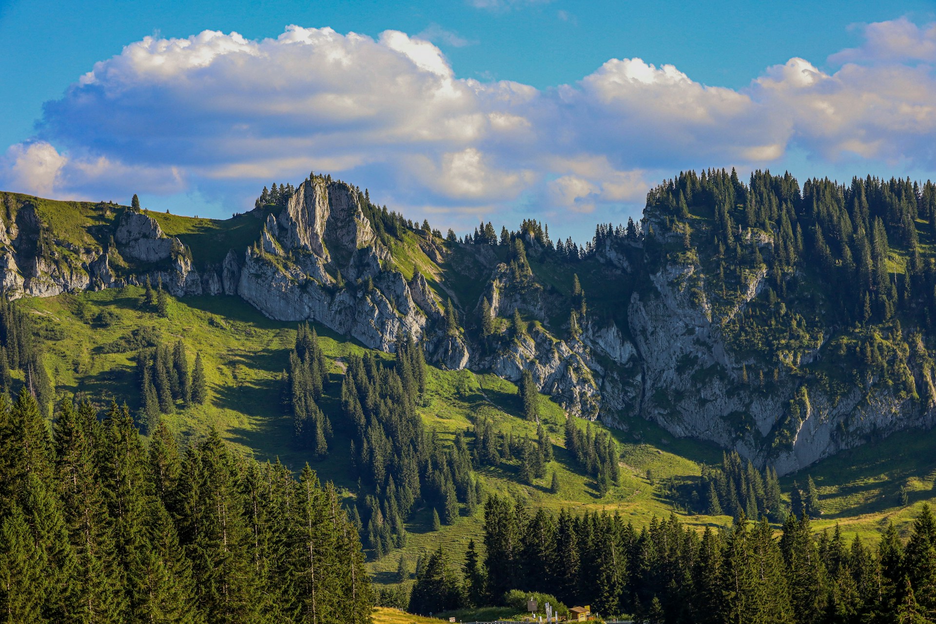 a scenic view of a mountain range with a house in the foreground