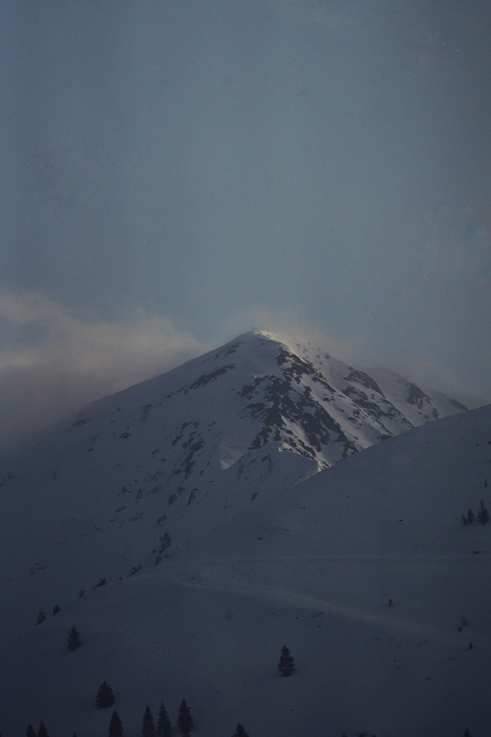 a snow covered mountain under a cloudy sky