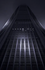 A sleek, modern skyscraper representing global financial power under a dark sky.