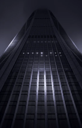 A sleek, modern skyscraper representing global financial power under a dark sky.