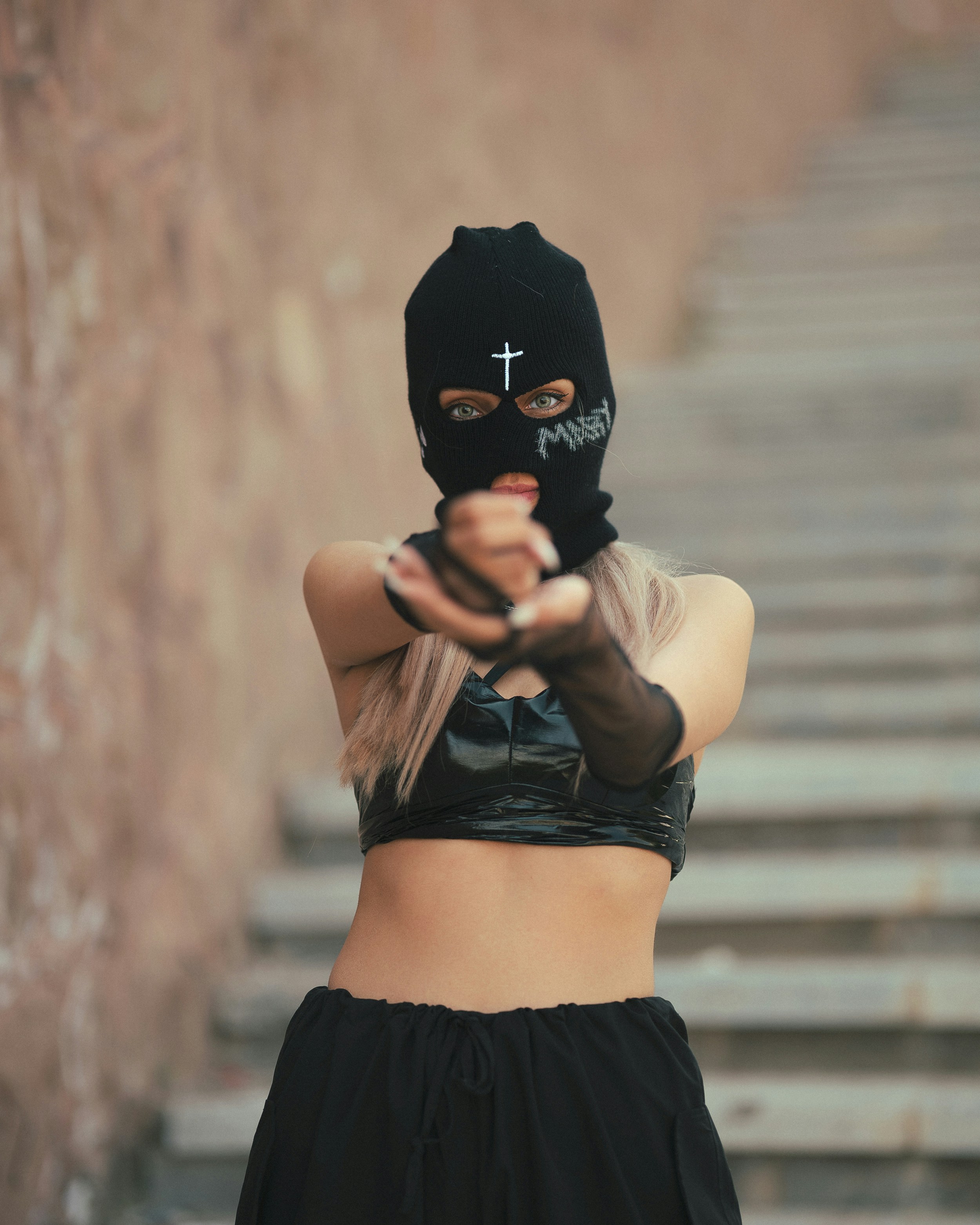A woman wearing a black mask pointing a gun