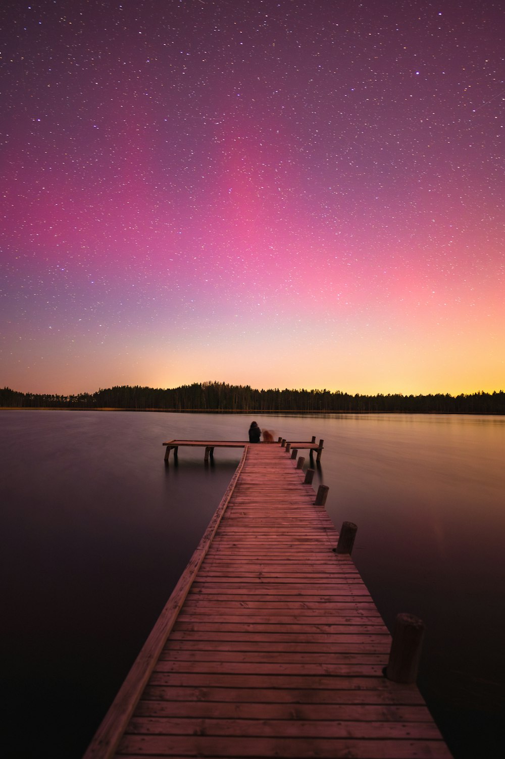 a wooden dock sitting on top of a lake under a purple sky