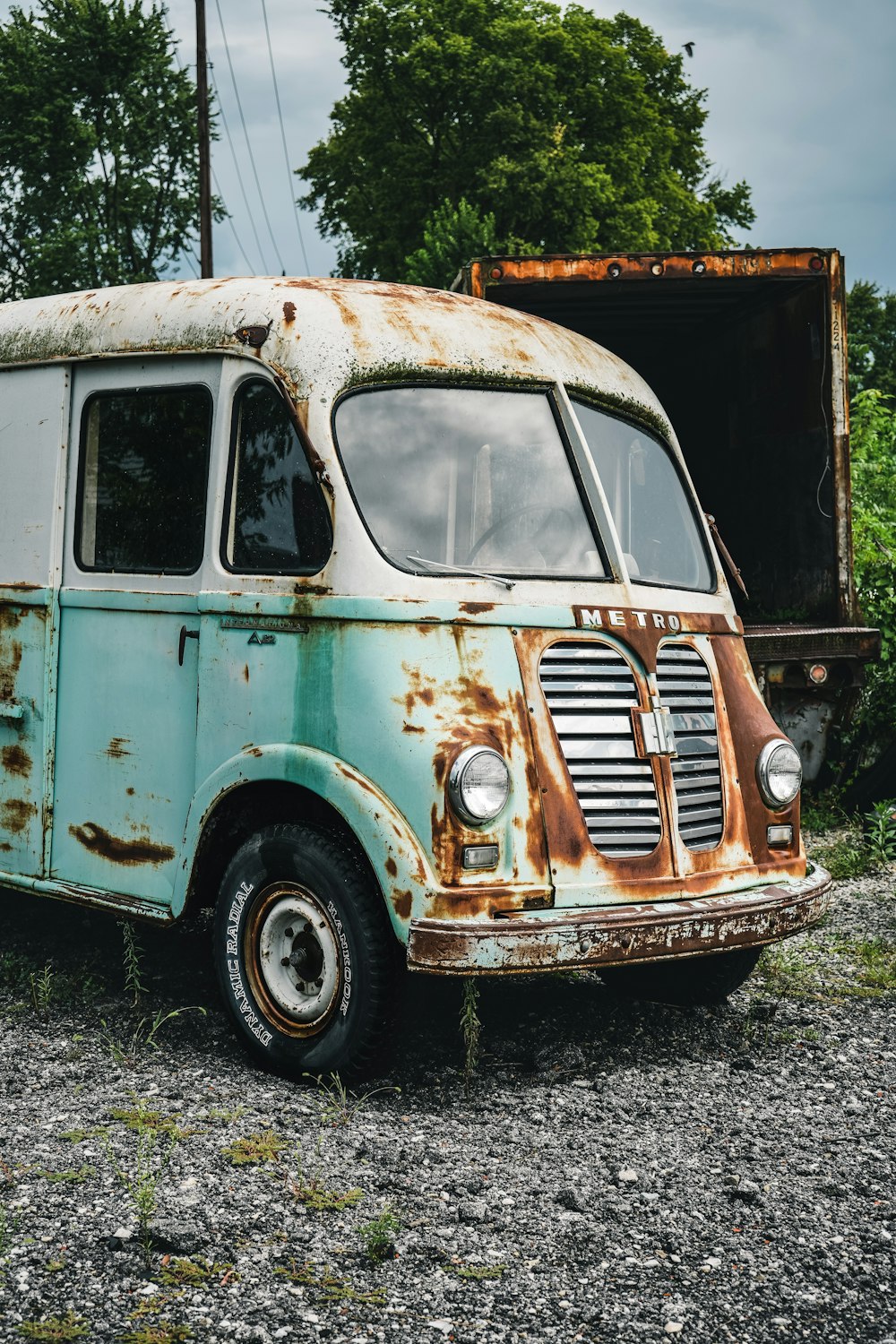 an old rusted out van sitting on a gravel road