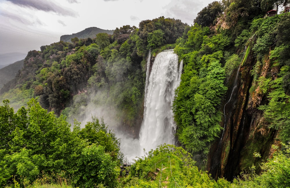 a large waterfall surrounded by lush green trees