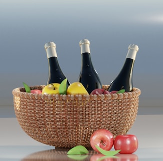 A woven basket contains three wine bottles, apples, and pears. The bottles are dark with light caps, and the fruits are vibrant, exhibiting reds and yellows. Additional apples and leaves are placed outside the basket on a reflective surface.